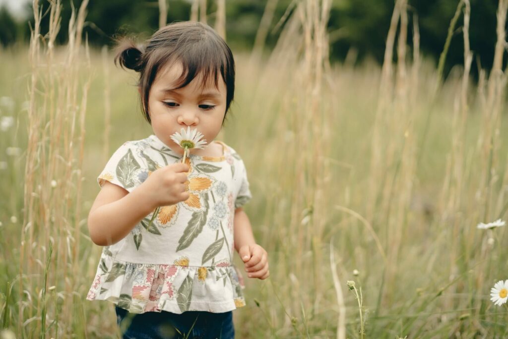 Girl smelling flower | What are some of the indicators of autism in a child?